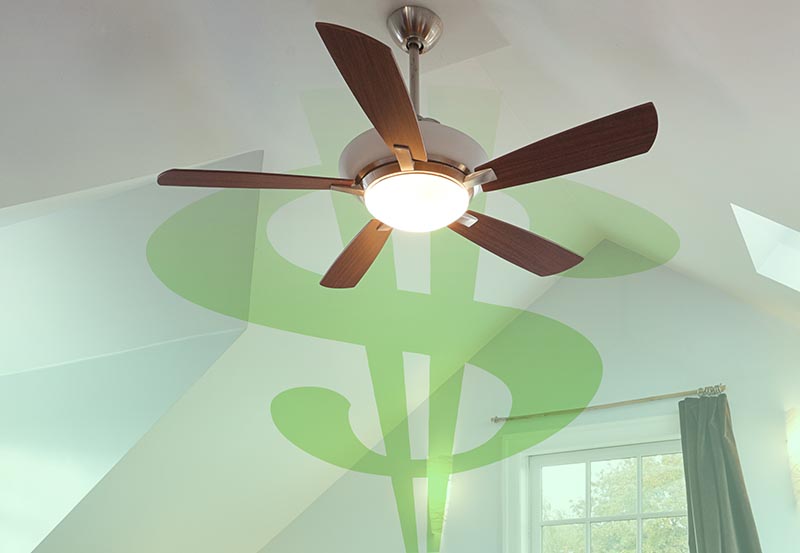 A modern ceiling fan with five wooden blades and an integrated central light fixture turned on, mounted to a vaulted white ceiling.