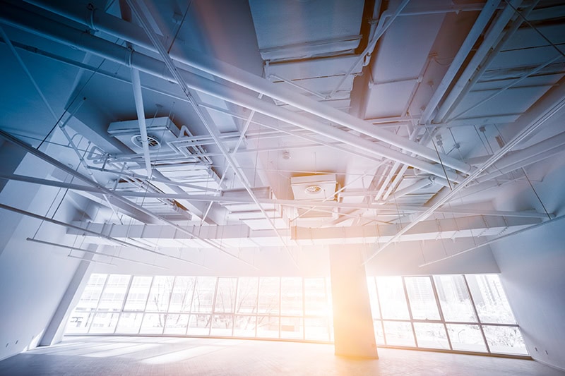 Inside of a warehouse with windows and sun shining through.