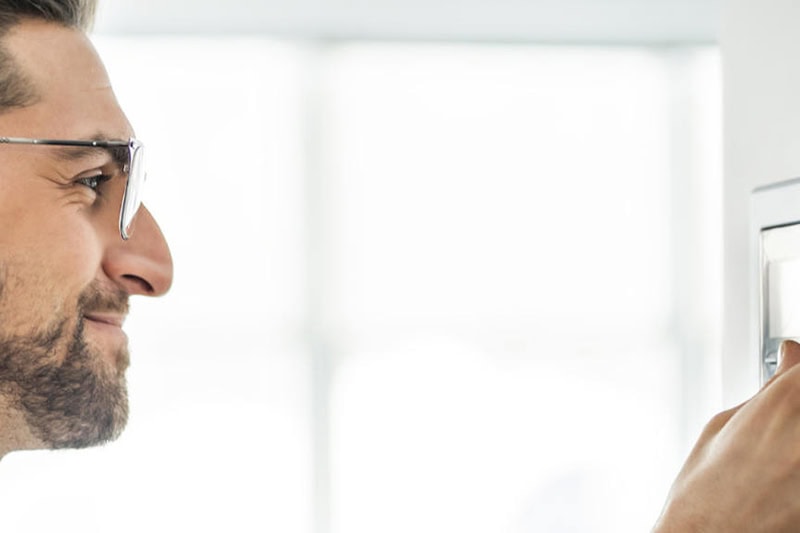 Find Your Ideal Thermostat Settings for Comfort and Savings in Las Vegas. Cheerful man set the thermostat at house.